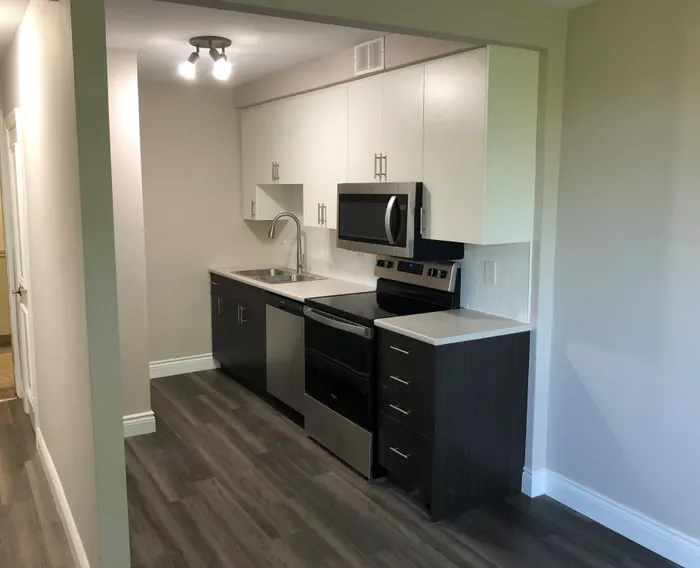 Completed interior of Saranac Apartments kitchen with modern lighting, cabinets, appliances, and floors
